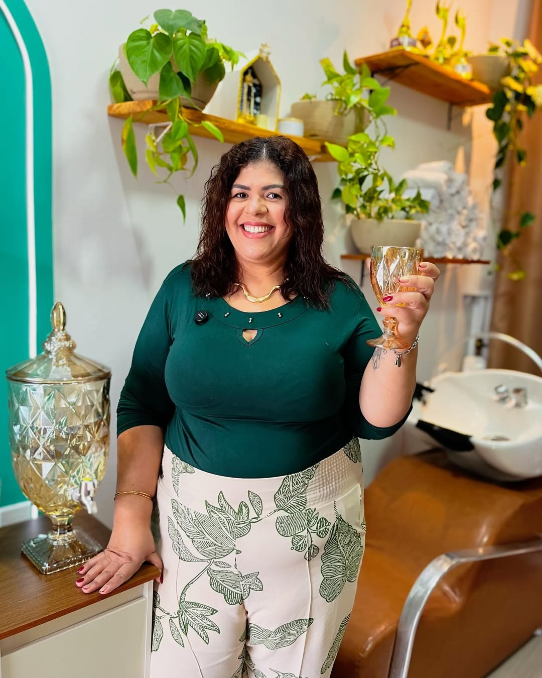 Ana Paula, cabeleireira e terapeuta capilar, sorrindo dentro do Studio Essence rodeada de plantas